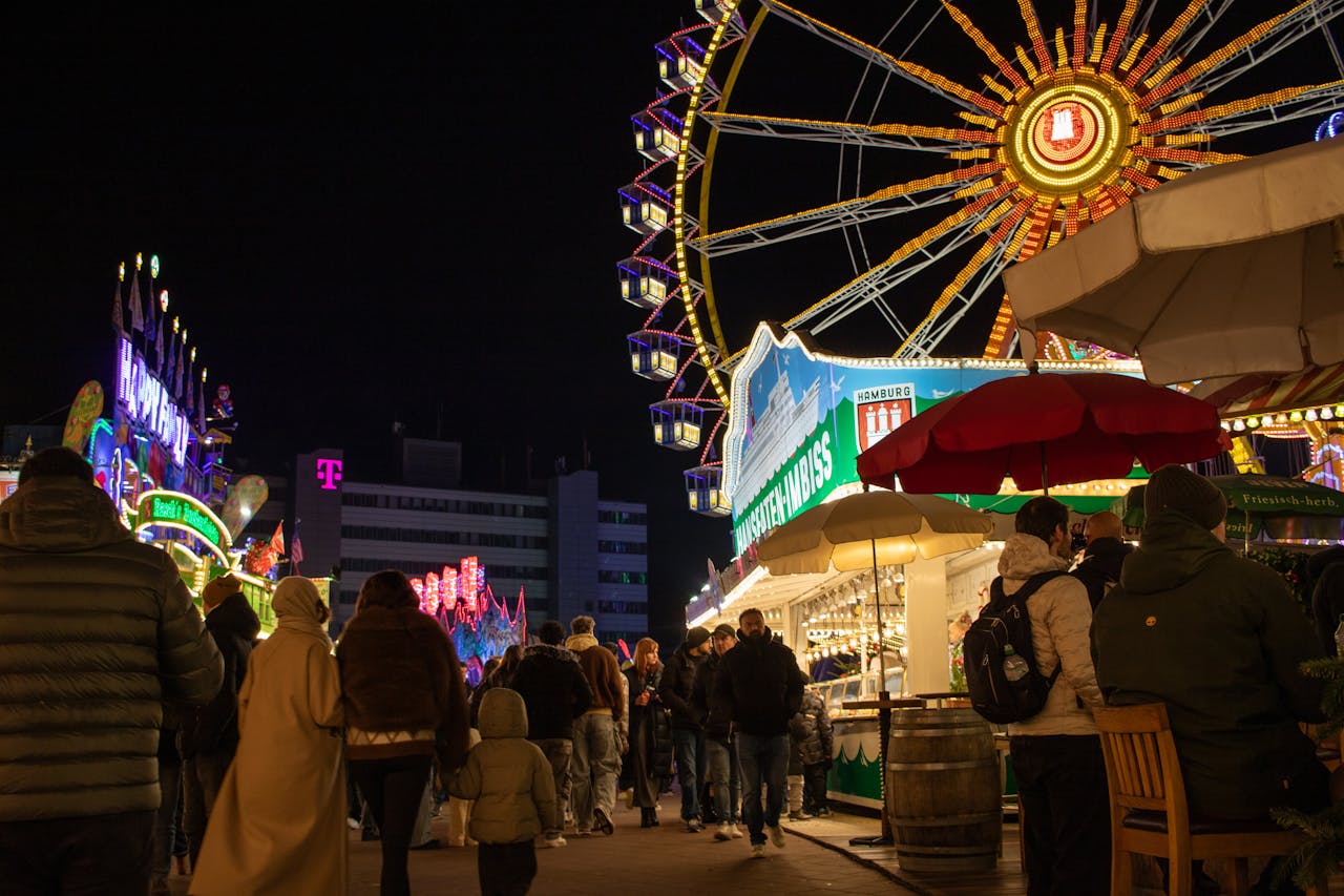 Experience the vibrant atmosphere of the Hamburger Dom carnival at night with illuminated attractions and crowds.